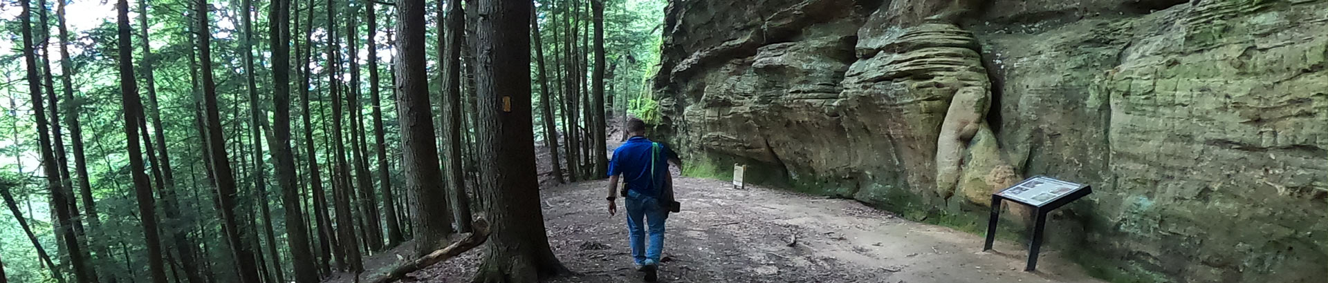 Rock formations and hiker along the trail before Whispering Cave Day Hike trail.